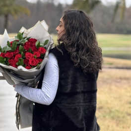 Woman holding a bouquet of red roses wrapped in paper