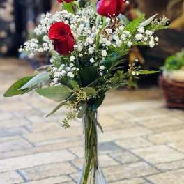 Red roses in a clear glass vase with white baby's breath