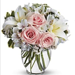 Pink roses and white lilies arranged in a clear glass vase