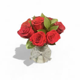 Red roses in a clear glass vase with a ribbon bow