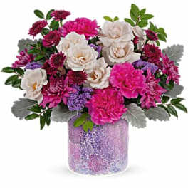 Pink and white mixed flower arrangement in a purple vase
