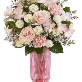 Pink roses and lilies arranged in a pink glass vase