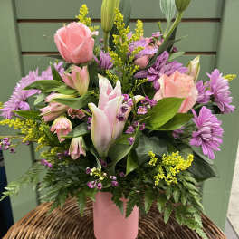 Pink roses and lilies in a pink vase with purple flowers