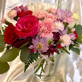 Mixed bouquet of roses, carnations, and daisies in a glass vase