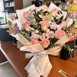 Pink rose bouquet with small daisies wrapped in pale paper and a silver bow