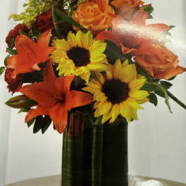 Orange lilies and sunflowers in a glass vase