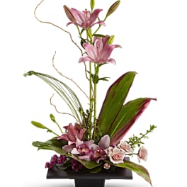 Pink lilies and orchids in a low rectangular vase