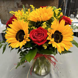 Sunflowers and red roses arranged in a glass vase