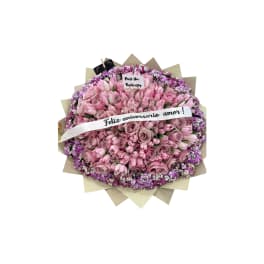 Round bouquet of pink roses with a white anniversary ribbon