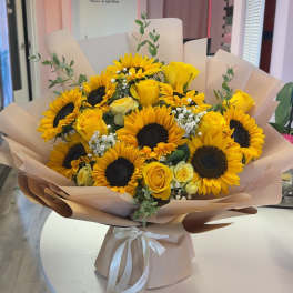 Bouquet of yellow sunflowers and roses wrapped in blush paper