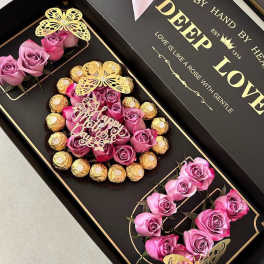 Black gift box with pink roses and chocolates arranged in compartments