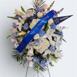 Standing floral spray with white lilies and blue flowers on an easel