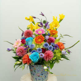 Colorful mixed flower arrangement in a floral tin container