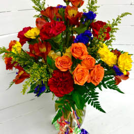 Colorful bouquet of roses, carnations, and daisies in a glass vase