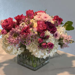 Pink and white mixed flower arrangement in a square glass vase