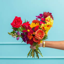 Handheld bouquet of mixed bright flowers in red, yellow, orange, and purple