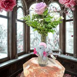 Pink rose in a glass vase with a small plush elephant