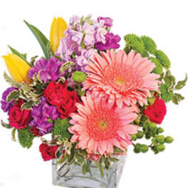 Mixed bouquet in a clear square vase with pink gerbera daisies and colorful blooms