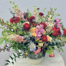 Large mixed bouquet in a round vase with red, pink, peach, and white flowers