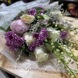 Bouquet of purple and white flowers wrapped in lace paper
