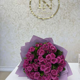 Bouquet of bright pink roses wrapped in lavender paper