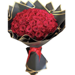 Bouquet of red roses wrapped in black paper with gold trim and a red ribbon