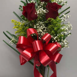 Red roses in a clear vase with a large red ribbon
