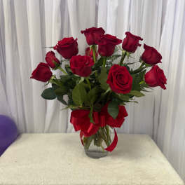 Red roses in a clear glass vase with a red ribbon