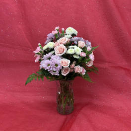 Pink and lavender flowers arranged in a glass vase