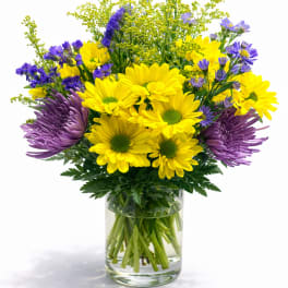 Yellow and purple flowers arranged in a clear glass vase
