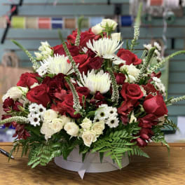 Red and white mixed flower arrangement in a round box
