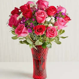 Bouquet of red and pink roses in a red glass vase