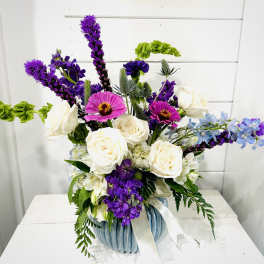 Purple and white mixed flower arrangement in a blue vase