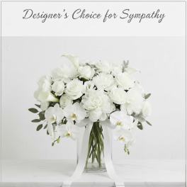 White floral arrangement in a clear glass vase with trailing ribbon