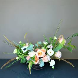 Low floral arrangement with peach and white roses in a black container