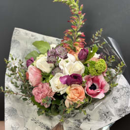 Mixed bouquet of pink, white, and peach flowers wrapped in printed paper