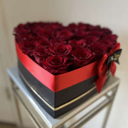 Heart-shaped box filled with red roses and tied with a red ribbon