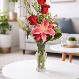 Red roses and pink lilies arranged in a clear glass vase