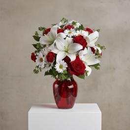 Red roses and white lilies in a red glass vase