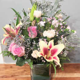 Pink and cream floral arrangement in a square glass vase
