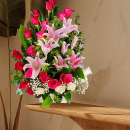 Pink lilies and roses arranged in a clear vase