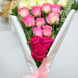 Bouquet of pink and white roses wrapped in white paper with a pink ribbon