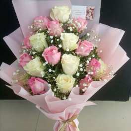 Bouquet of pink and white roses wrapped in pale pink paper