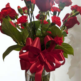 Red roses and carnations in a glass vase with a red ribbon
