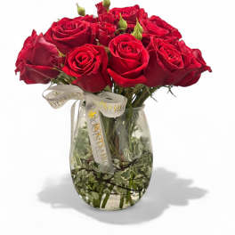 Red roses arranged in a clear glass vase with a ribbon bow