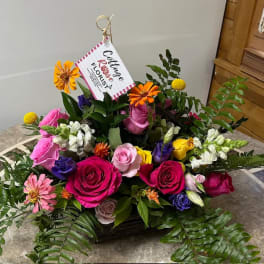 Mixed bouquet of roses, daisies, and snapdragons in a basket