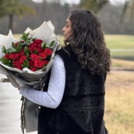 Woman holding a bouquet of red roses wrapped in paper