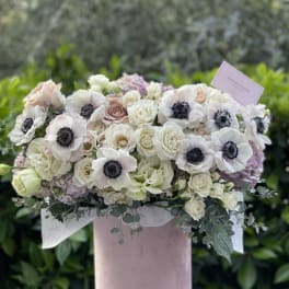 Blush and white floral arrangement in a pink hat box