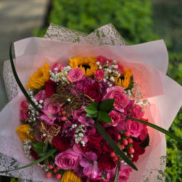 Bouquet of pink and red roses with yellow sunflowers in pink wrap
