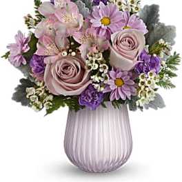 Pastel bouquet of pink roses, lavender daisies, and alstroemeria in a ribbed lavender glass vase